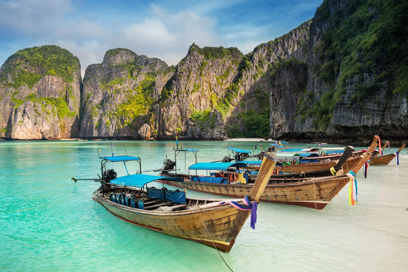 Thailand sea beach view round with steep limestone hills with many traditional longtail boats parking at Maya Bay, Ko Phi Phi Leh island, part of Krabi, Andaman Sea