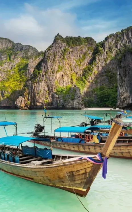 Thailand sea beach view round with steep limestone hills with many traditional longtail boats parking at Maya Bay, Ko Phi Phi Leh island, part of Krabi, Andaman Sea
