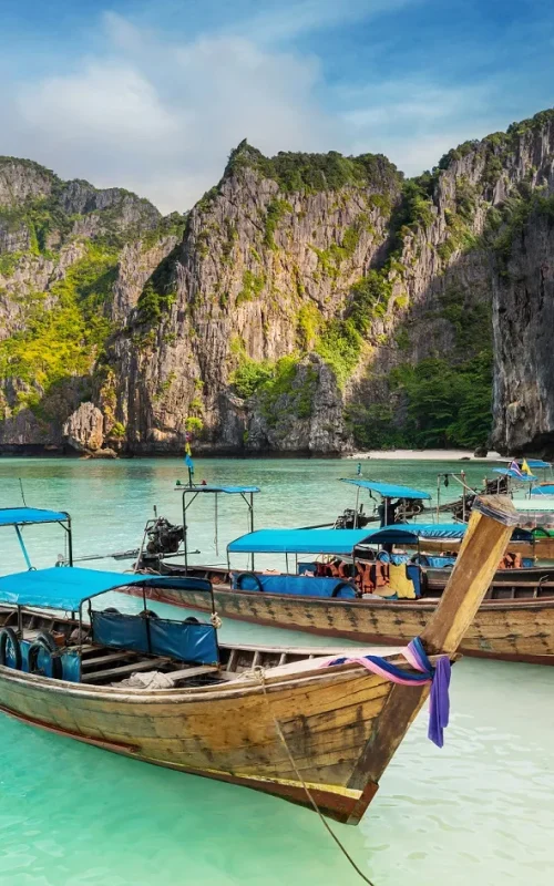 Thailand sea beach view round with steep limestone hills with many traditional longtail boats parking at Maya Bay, Ko Phi Phi Leh island, part of Krabi, Andaman Sea
