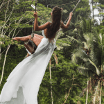 Young lady in a white dress on a Jungle swing in Ubud